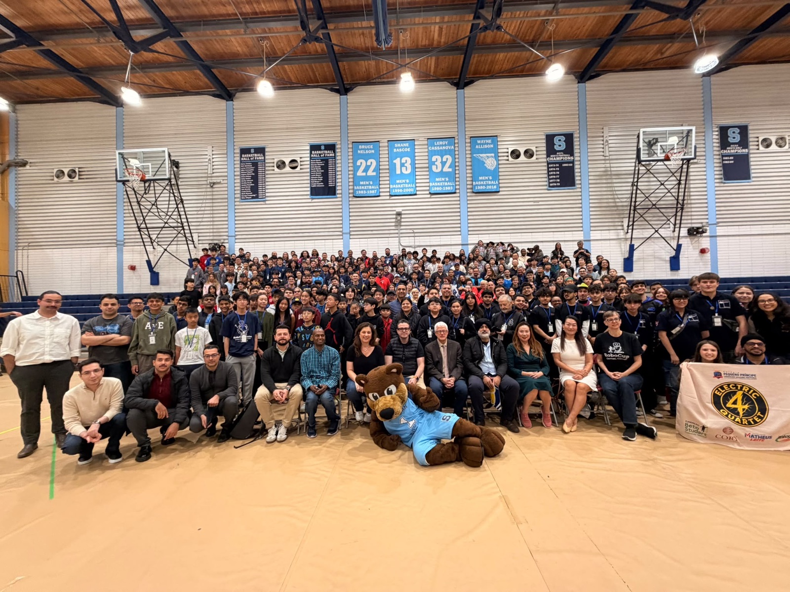 Foto grupal de estudiantes, mentores, organizadores e invitados llenando el gimnasio en la ceremonia de clausura en Brampton.